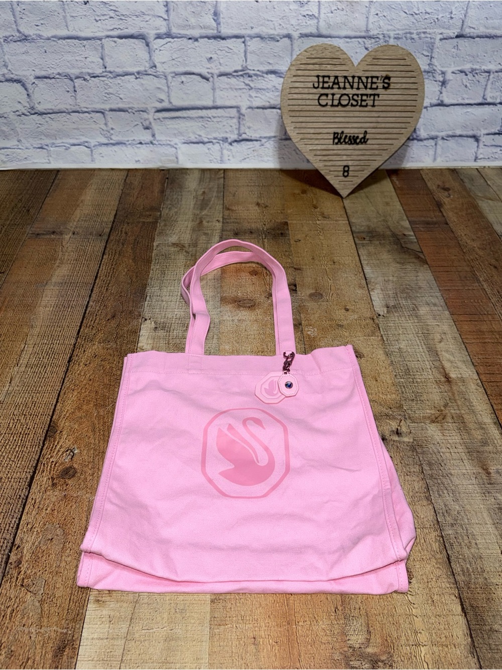 Swarovski pink canvas tote with dual shoulder straps. Features a debossed swan e